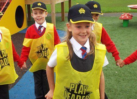 A girl wearing a yellow vest that says play leader