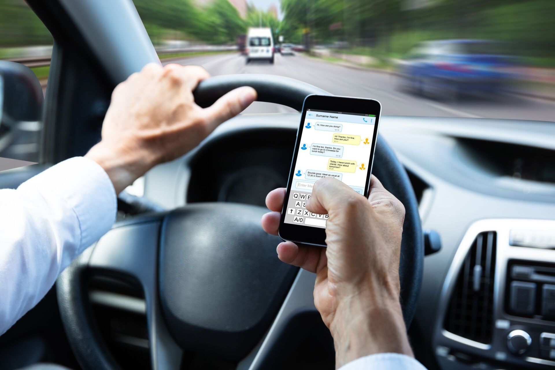 Driver using a smartphone while steering a car on the road