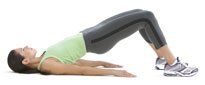 A woman is doing a bridge exercise on the floor.