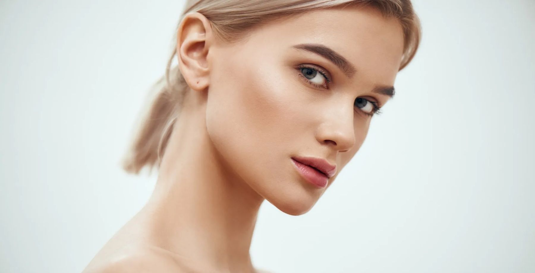 Portrait of a blonde person with a calm expression against a white background