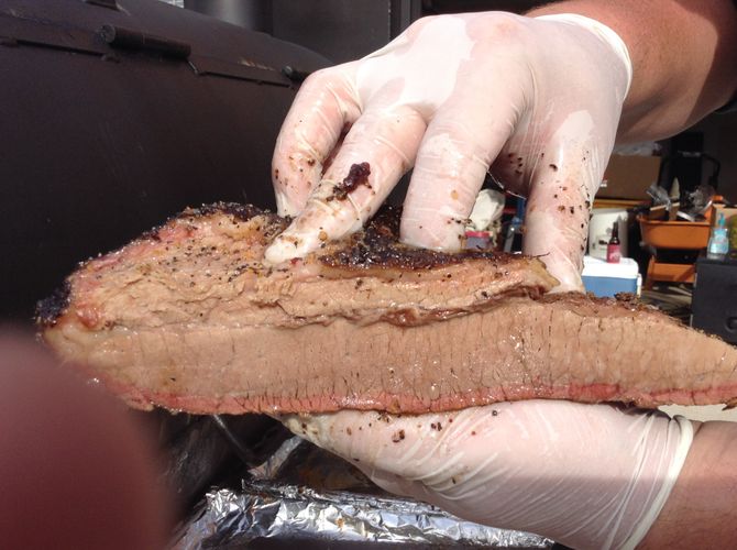 A person wearing white gloves is holding a piece of meat