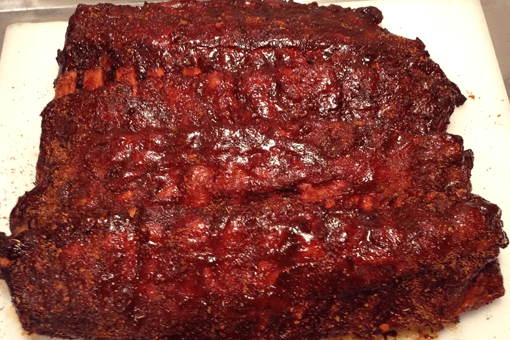 A piece of meat with sauce on it is on a cutting board