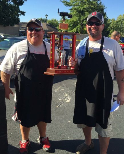 Two men standing next to each other holding a trophy