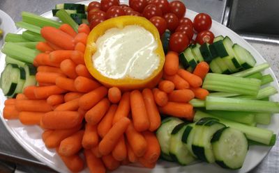 A white plate topped with carrots celery tomatoes and cucumbers