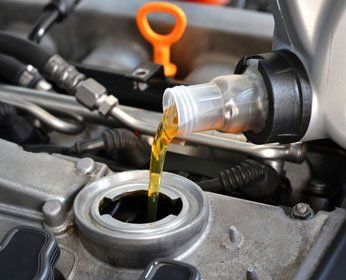 Mechanic putting fresh motor oil in car — car in Poughquag, NY Mechanic putting fresh motor oil in car — car in Poughquag, NY