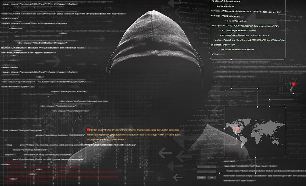 A man in a hoodie is standing in front of a computer screen.