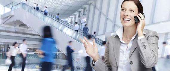 A woman is talking on a cell phone in front of an escalator.
