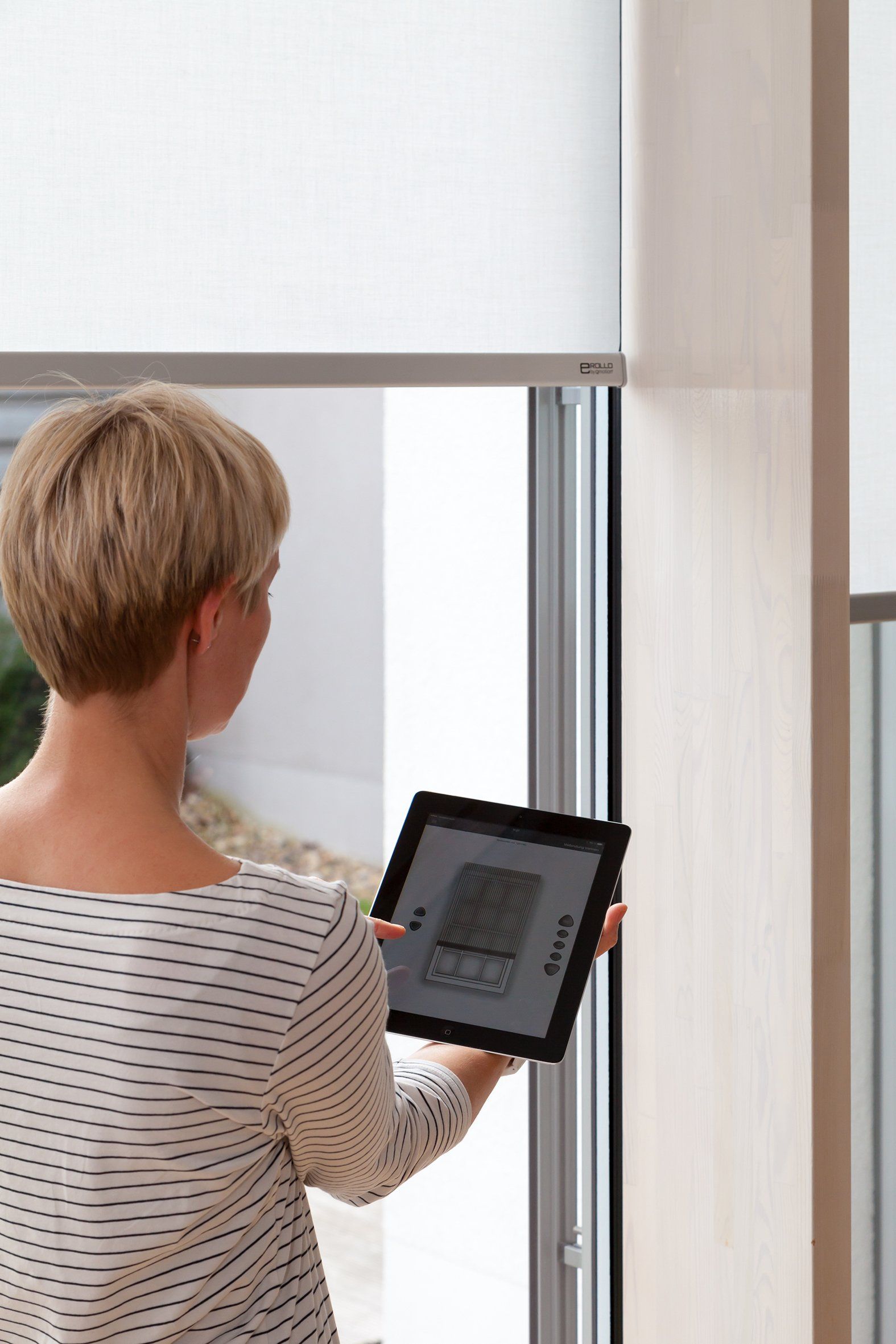 Frau mit Ipad vor Fensterrollo