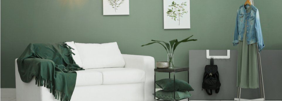 Die aktuellen Trends, wie Sie Ihren kahlen Wänden frisches Lebenverleihen Wohnzimmer weißes Sofa und mattgrüne Wandfarbe mit grüner Pflanze und Kissen
