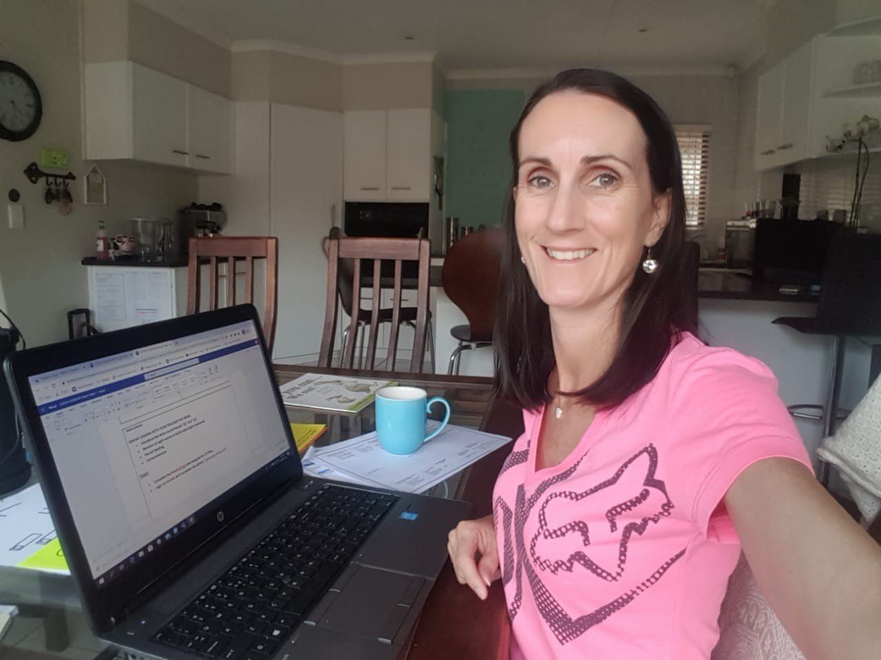 A woman in a pink fox shirt is sitting in front of a laptop computer
