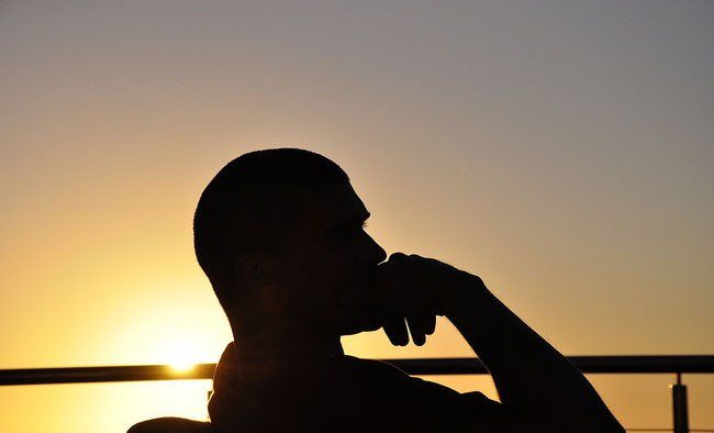 A silhouette of a man sitting in front of a sunset
