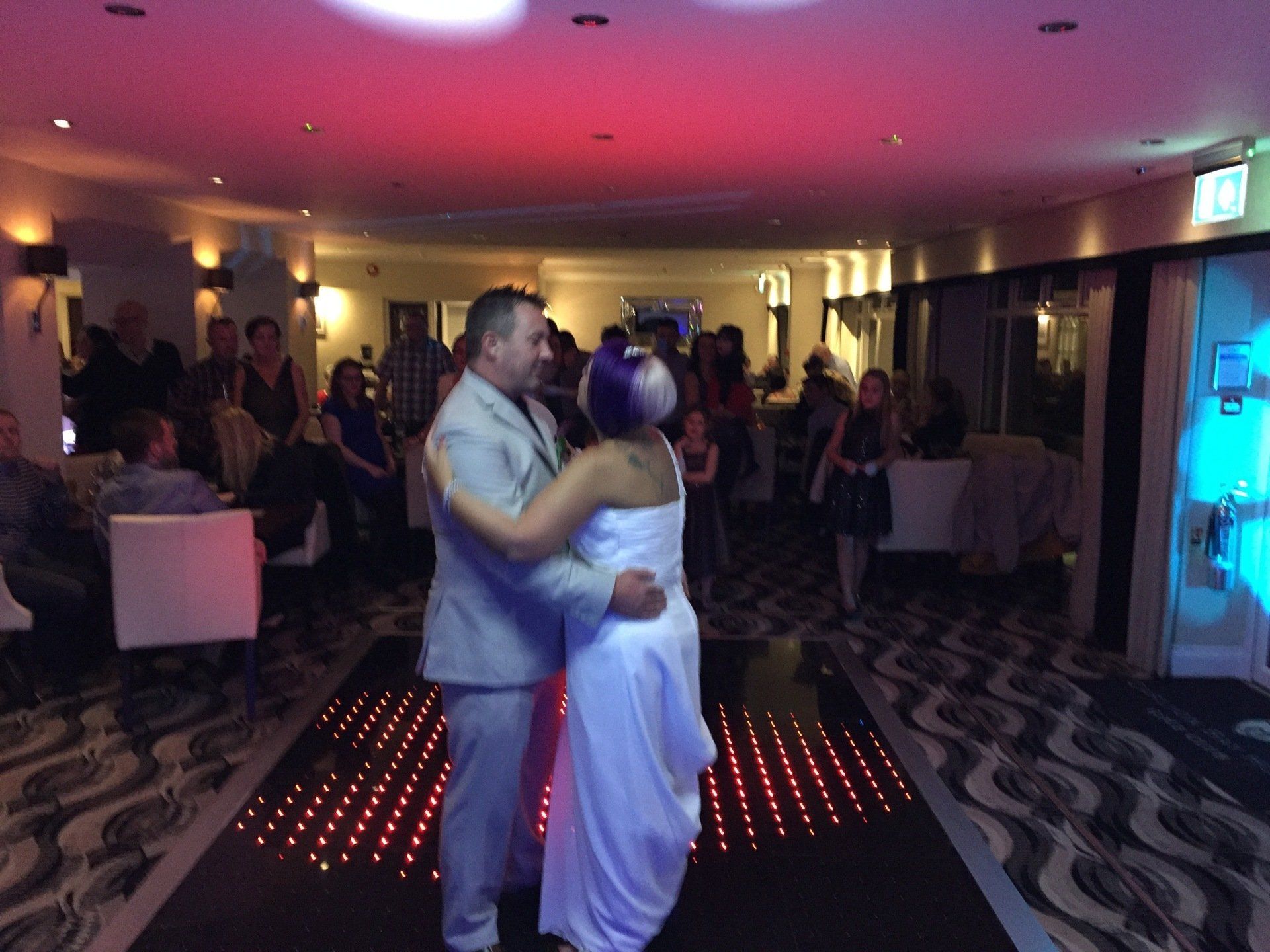 Couple dancing on a lit dance floor at a wedding reception.