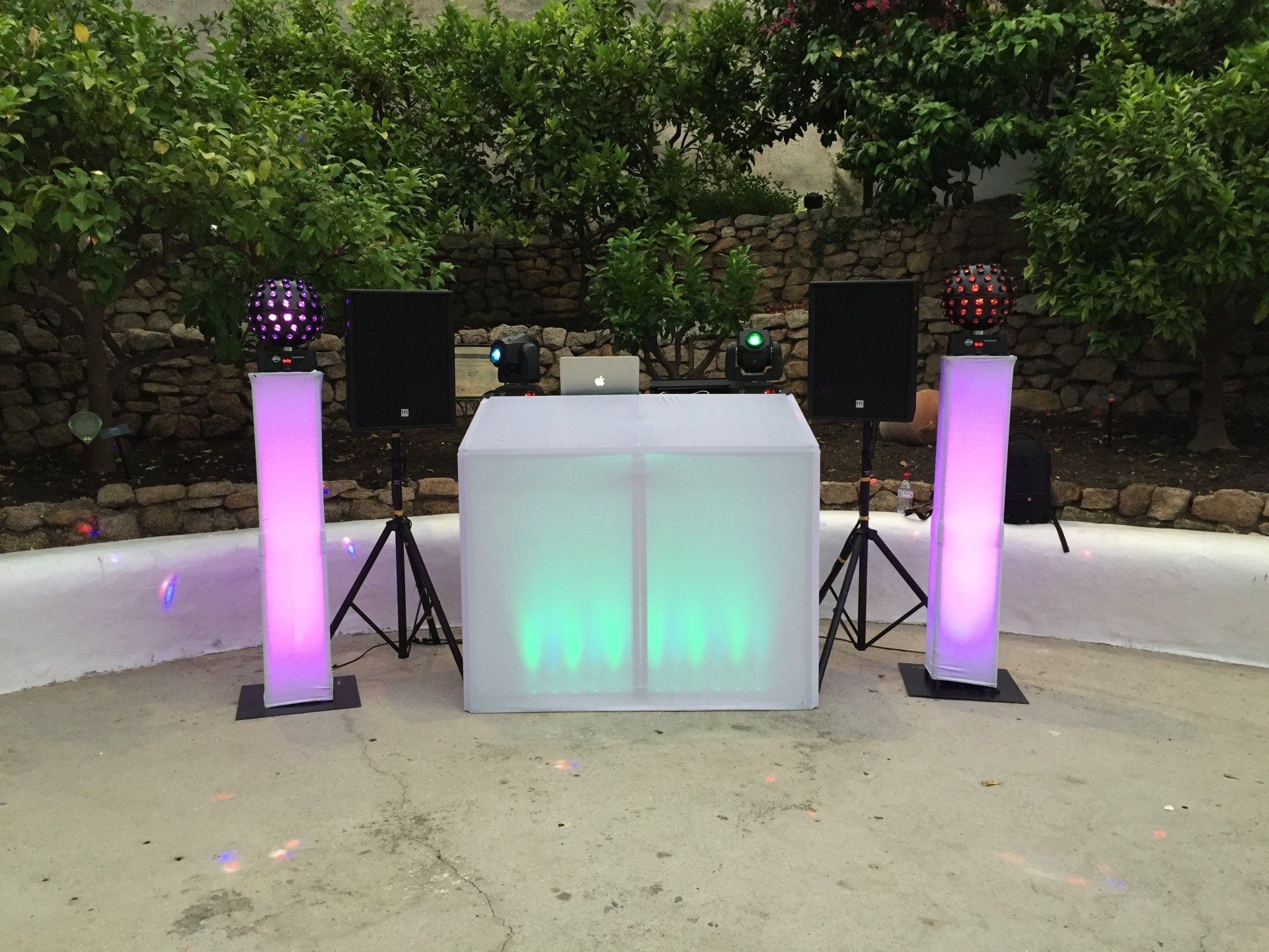 DJ setup outdoors with illuminated columns, speakers, and a central booth.