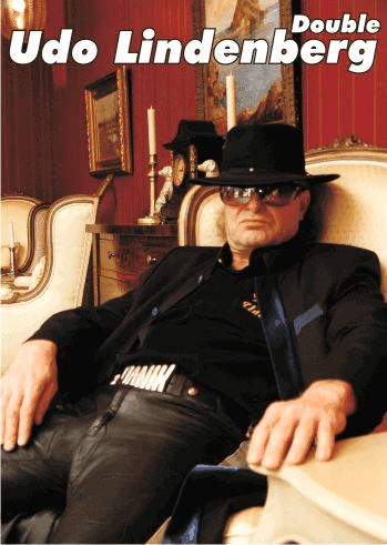 Ein Mann mit Hut und Sonnenbrille sitzt auf einem Stuhl, über ihm stehen die Worte „double udo lindenberg“