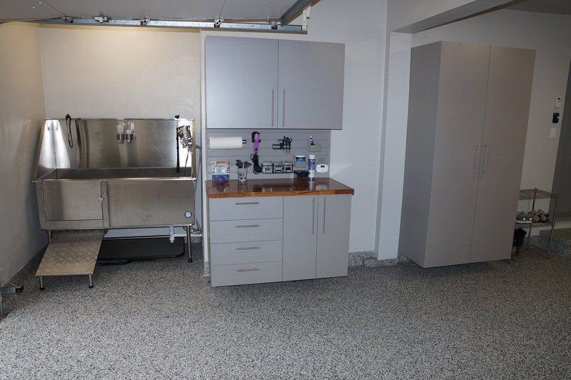 Gray cabinets beside a stainless utility sink on a flake garage floor
