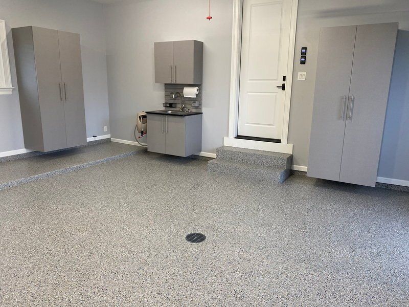 Gray tall cabinets and a small sink station on a gray flake garage floor