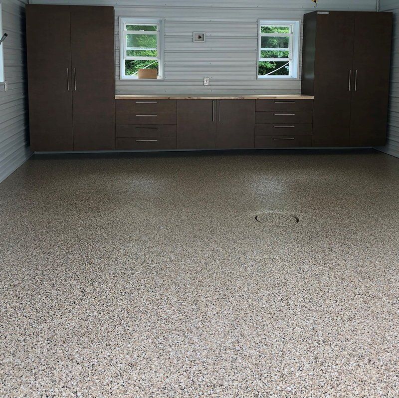 Dark garage cabinets with a workbench under two windows on a flake floor