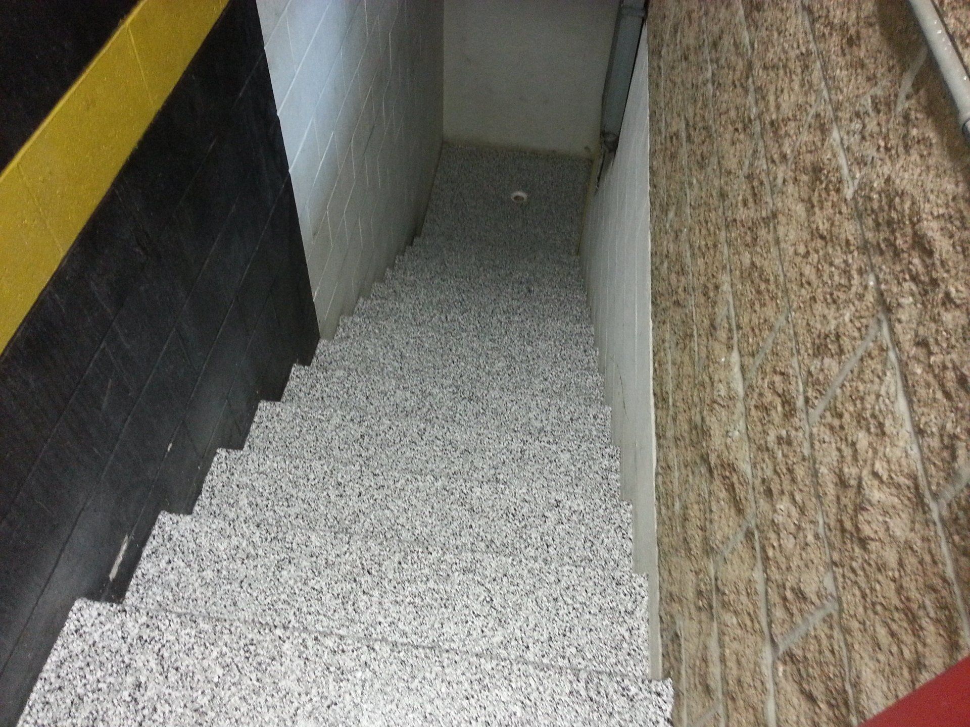 Stairwell coated in gray flake polyaspartic beside a stone wall