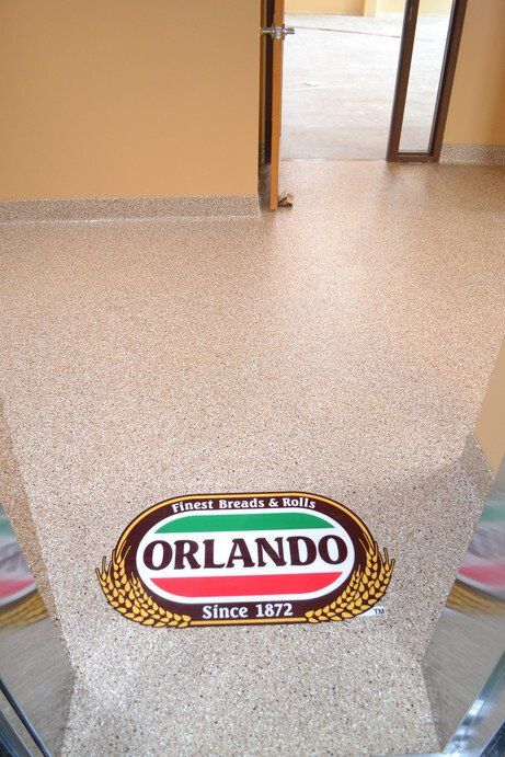 Tan flake commercial floor with an inlaid Orlando bakery logo