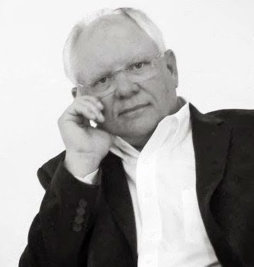 A black and white photo of a man in a suit and glasses.