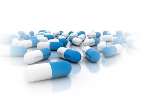 A collection of white and blue medical capsules scattered on a clean, reflective white background.