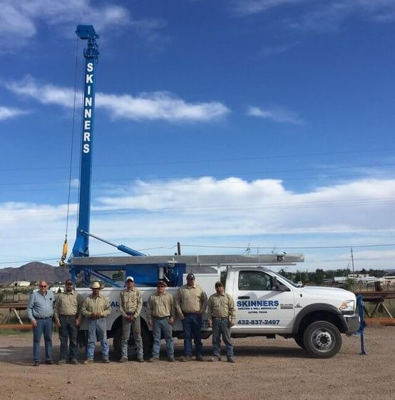 workers posing with water well drilling truck