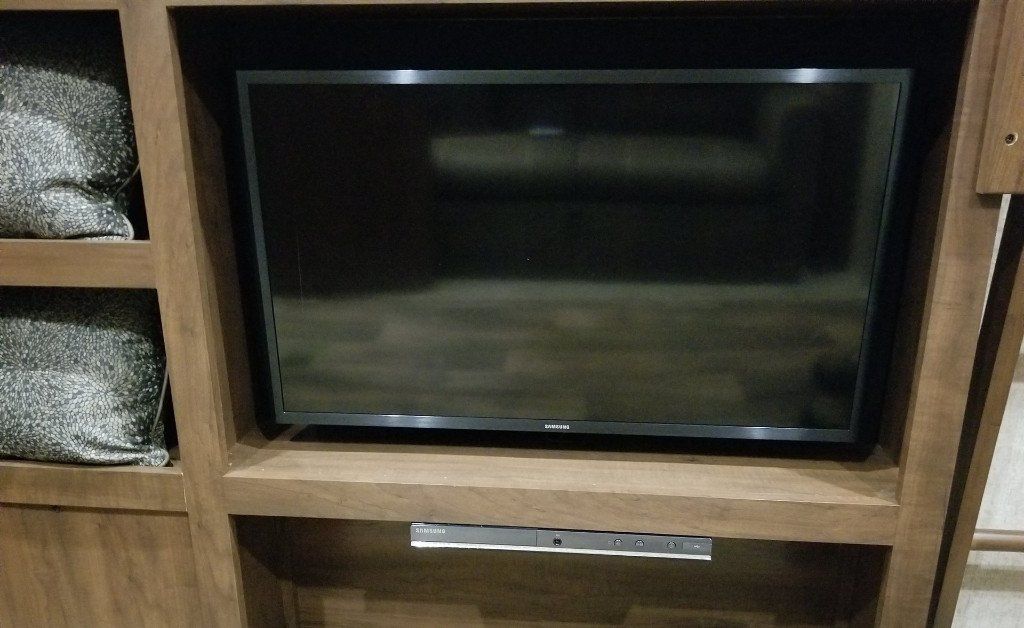 A flat screen tv is sitting on top of a wooden entertainment center.