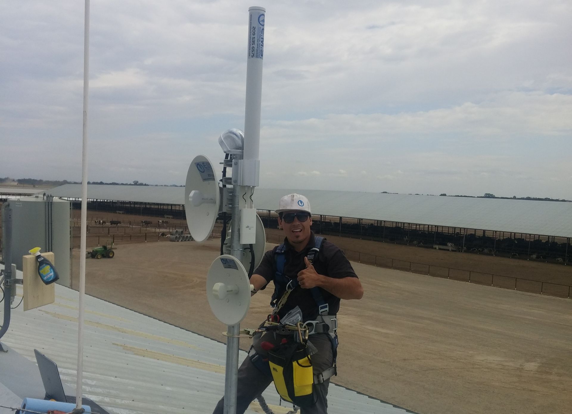 Eugene Silva is standing next to a Internet radio dish and giving a thumbs up