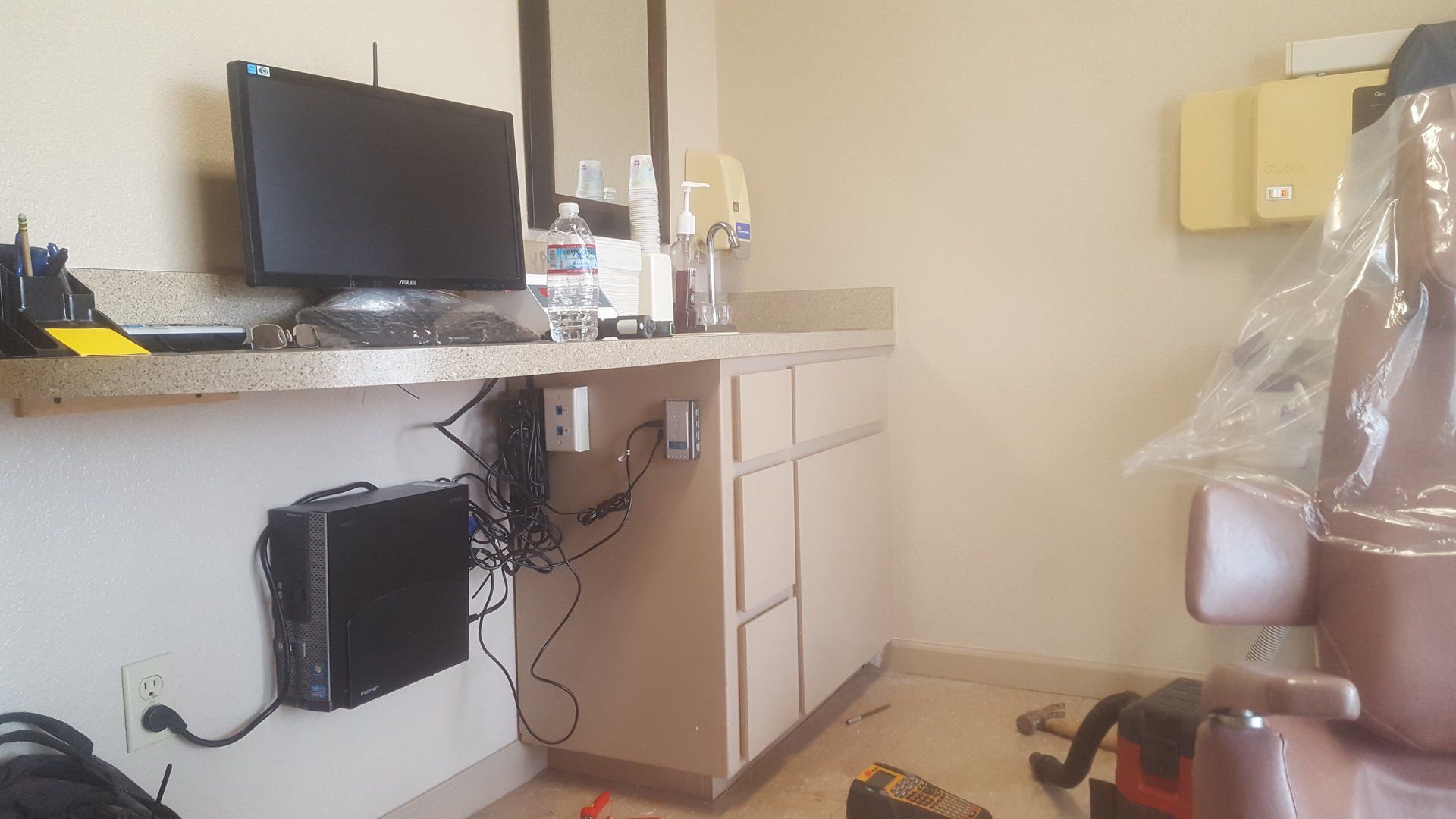 A dental office with a dental chair and a computer on the counter.