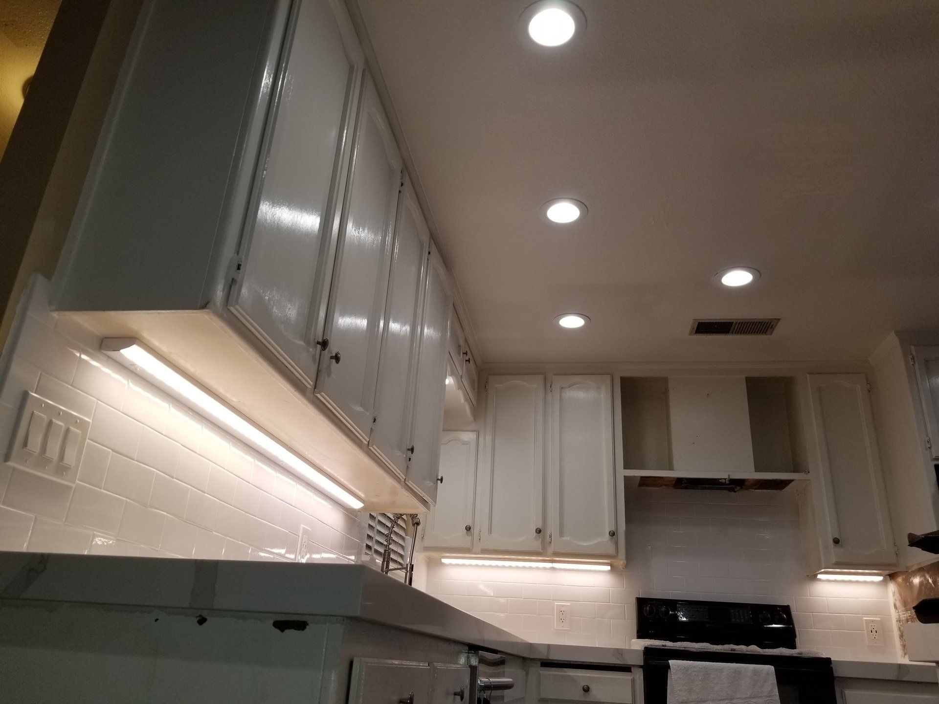 A kitchen with white cabinets and a black stove top oven.