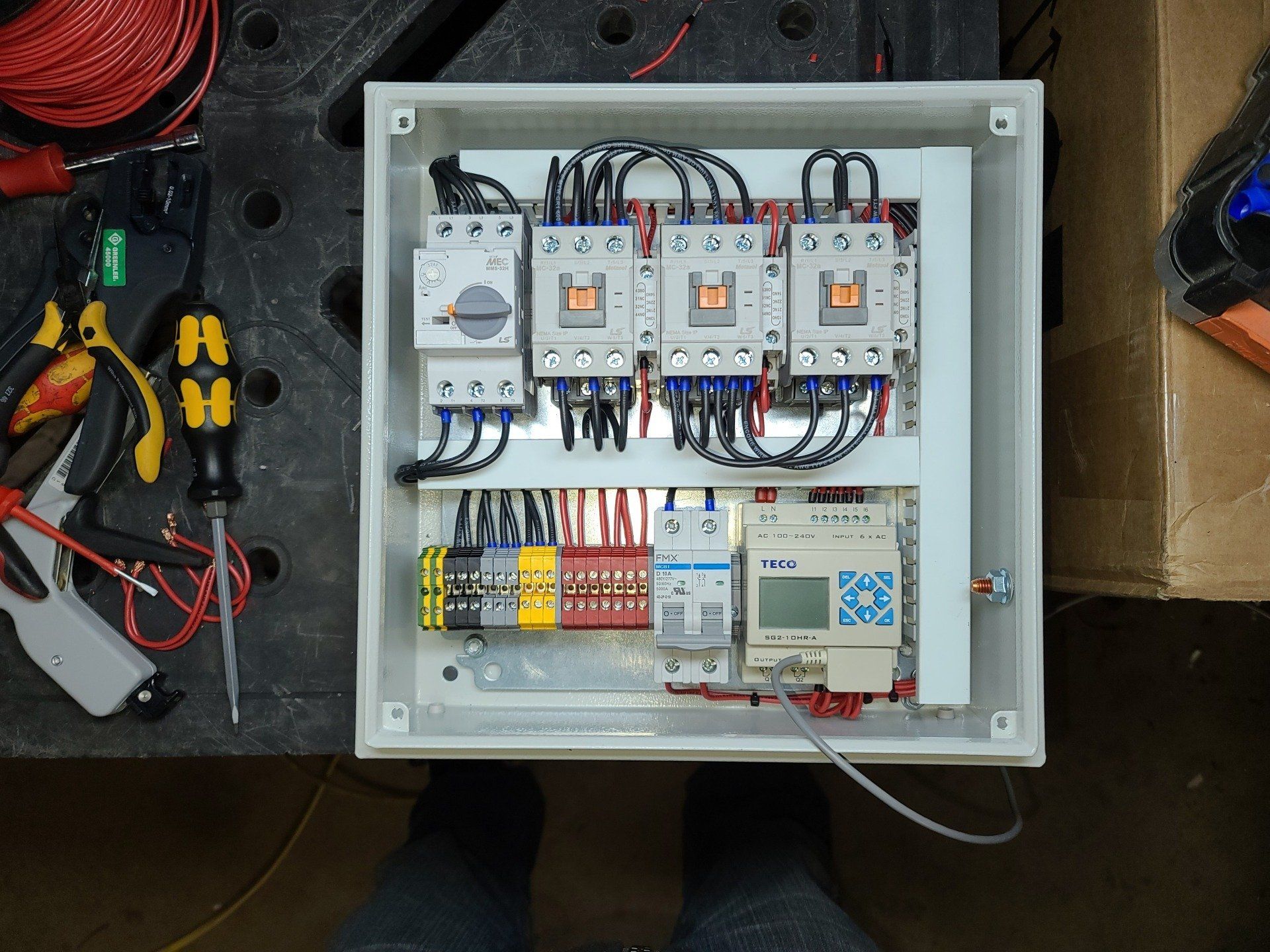 A person is working on a electrical box with many wires