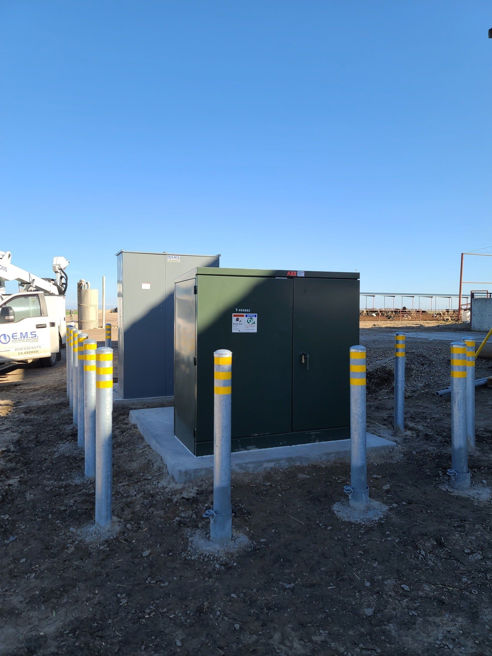 A green box is sitting in the middle of a dirt field surrounded by yellow poles.