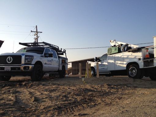 Two white EMS trucks are parked next to each other on a dirt road