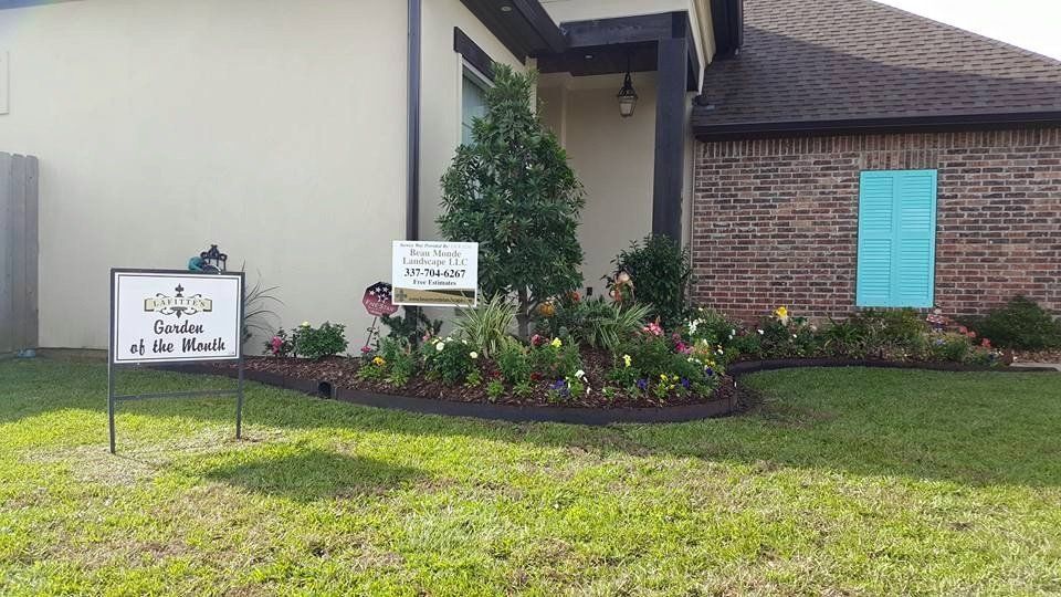 A house with a flower bed and signs on the lawn.
