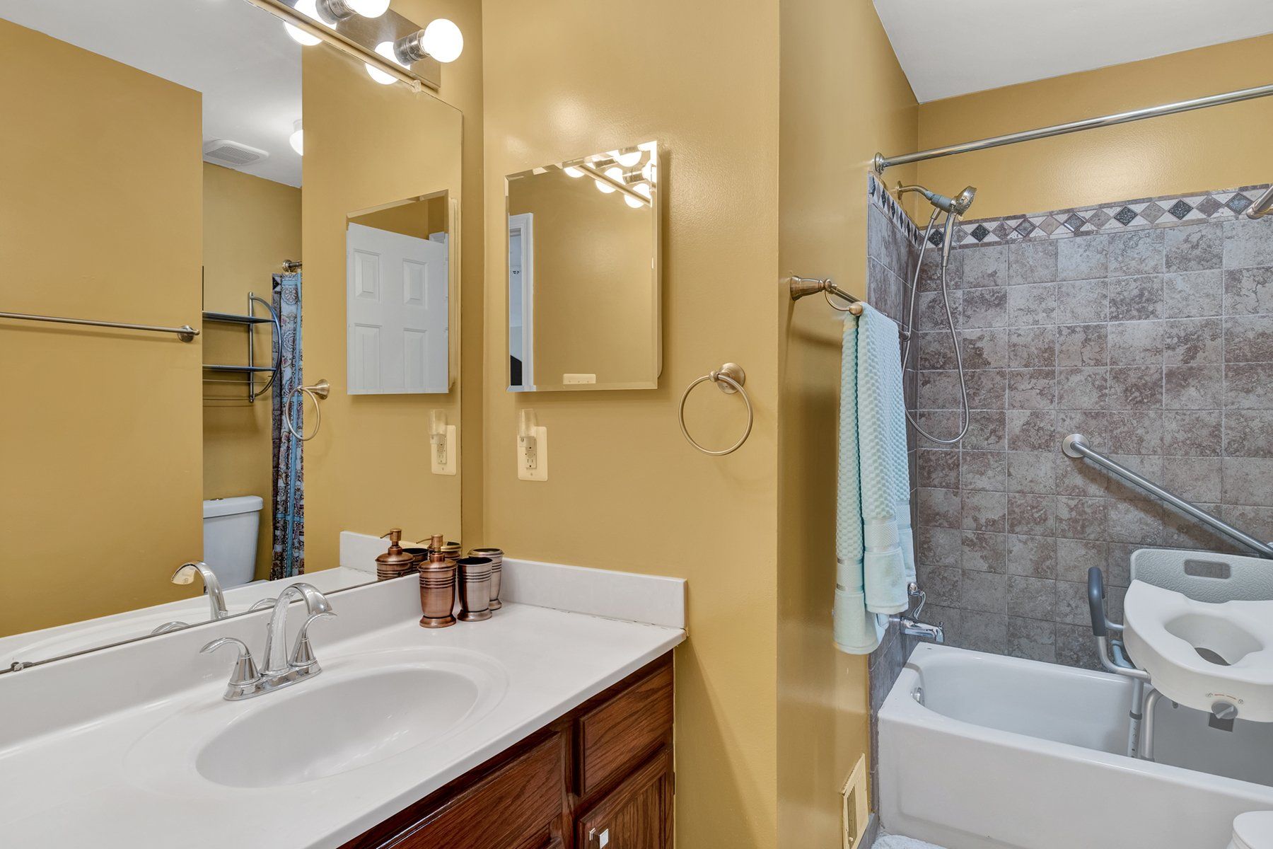 A bathroom with a sink , mirror , tub and toilet.