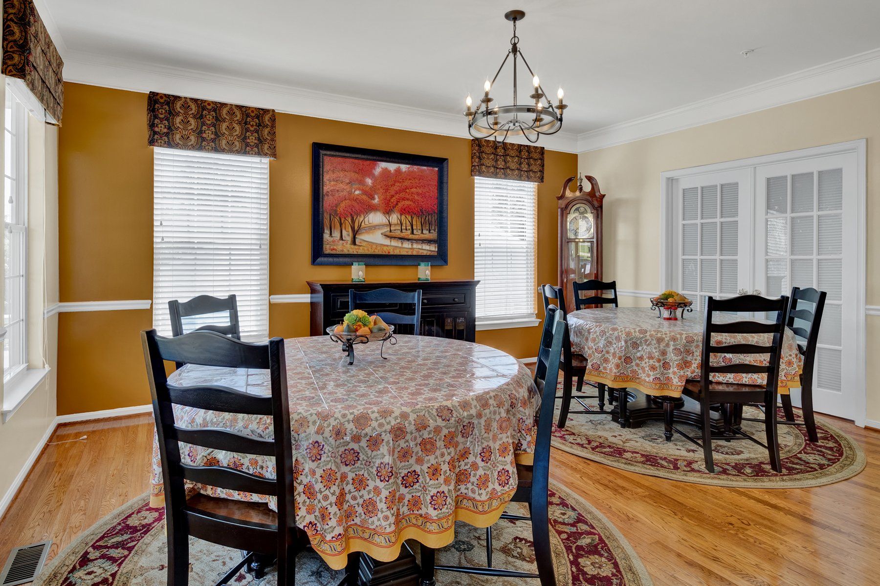 A dining room with a round table and chairs and a chandelier.