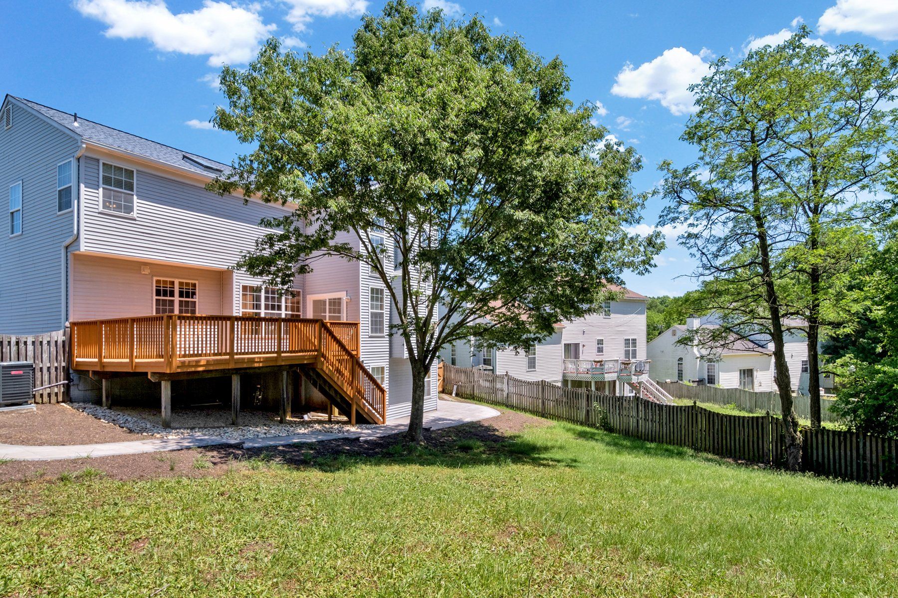 The backyard of a house with a wooden deck and a fence.