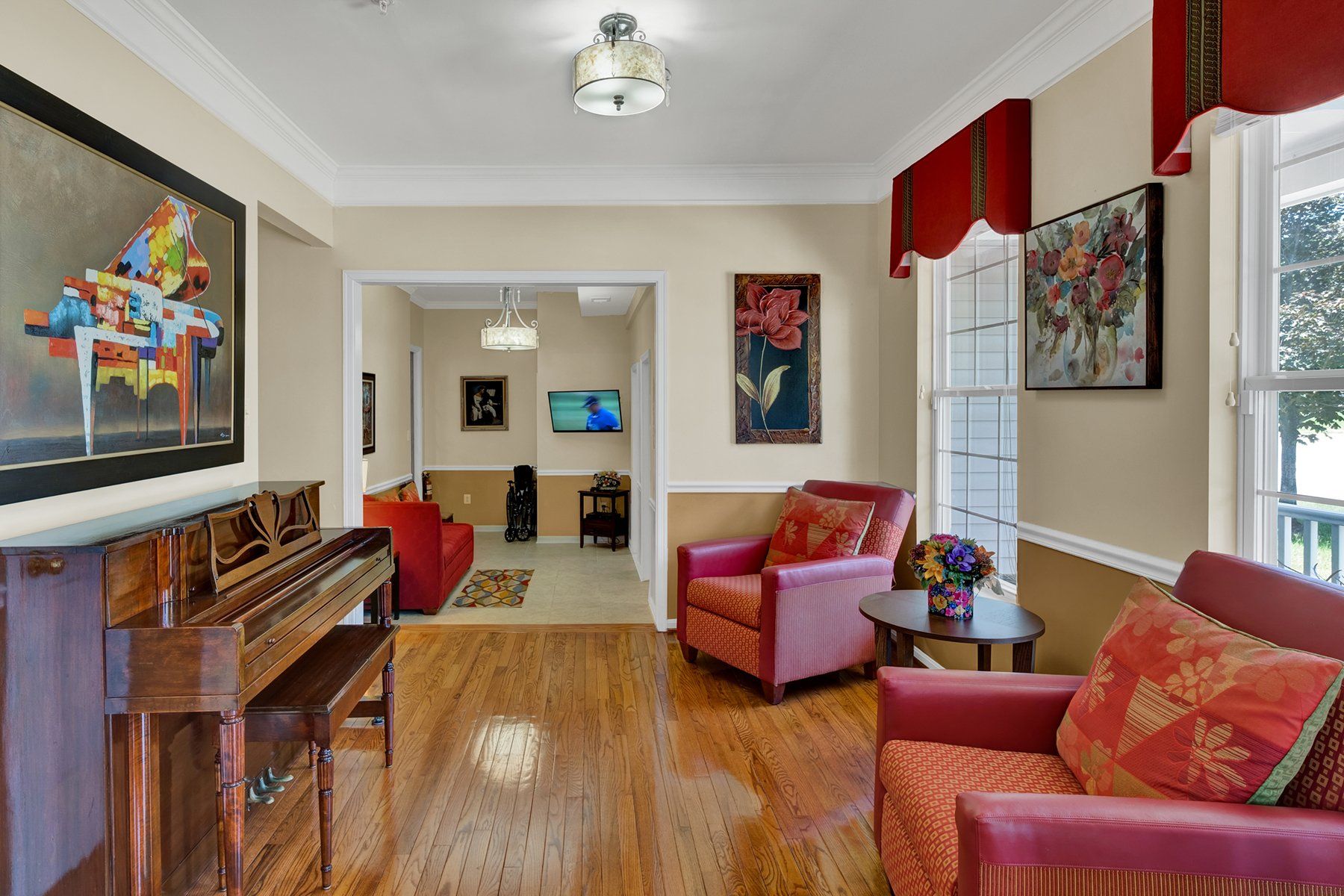 A living room with a piano , chairs , and a painting on the wall.