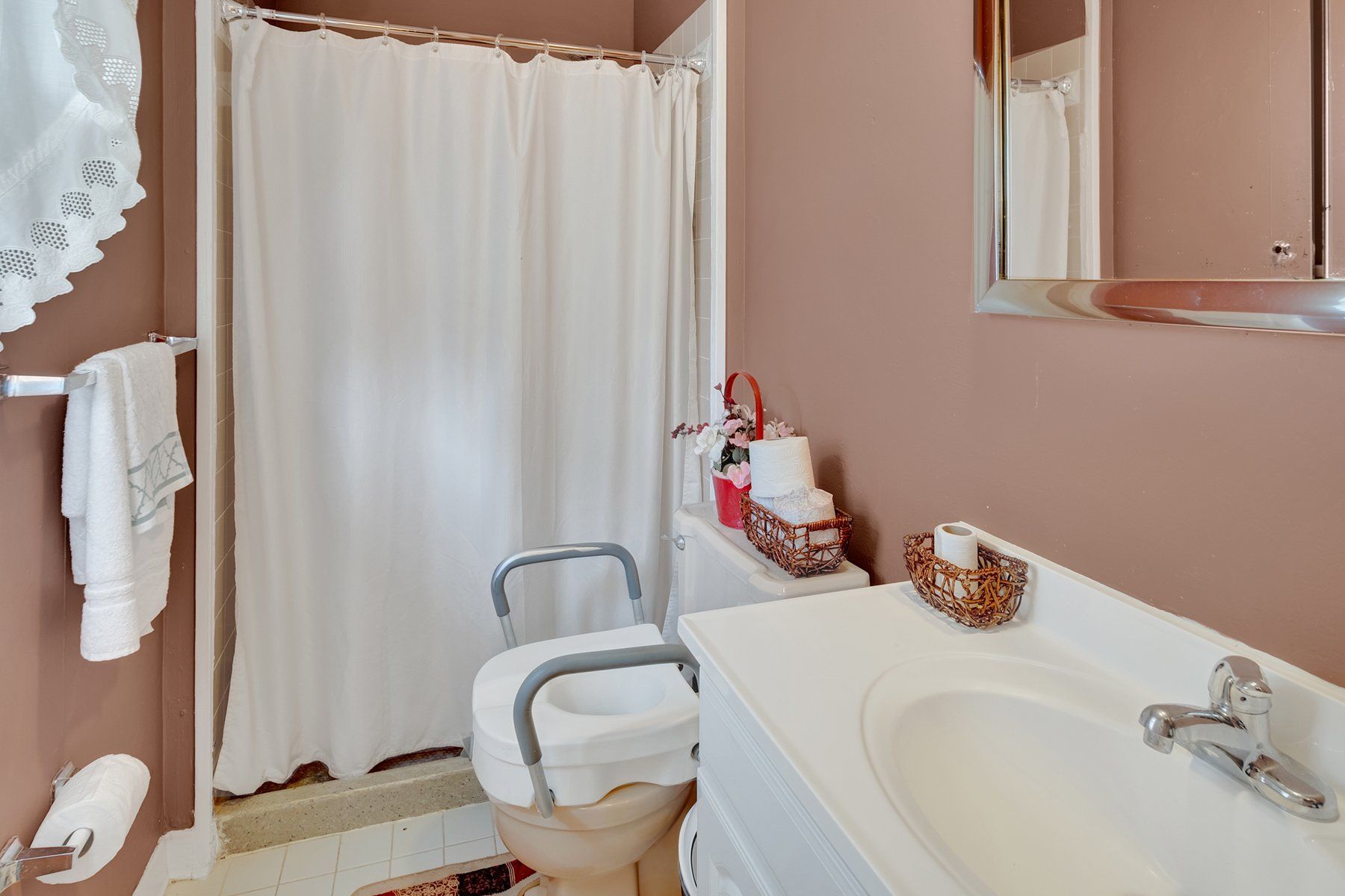 A bathroom with a toilet , sink , mirror and shower curtain.