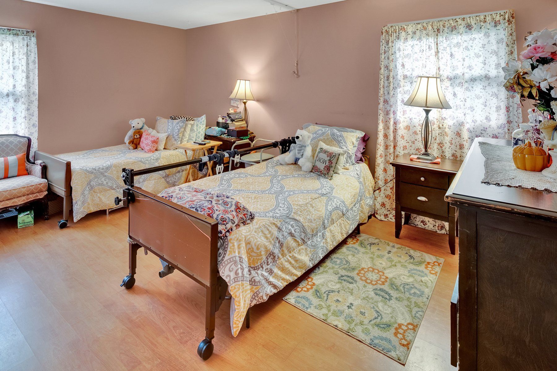 A bedroom with two beds , a nightstand , a chair and a dresser.