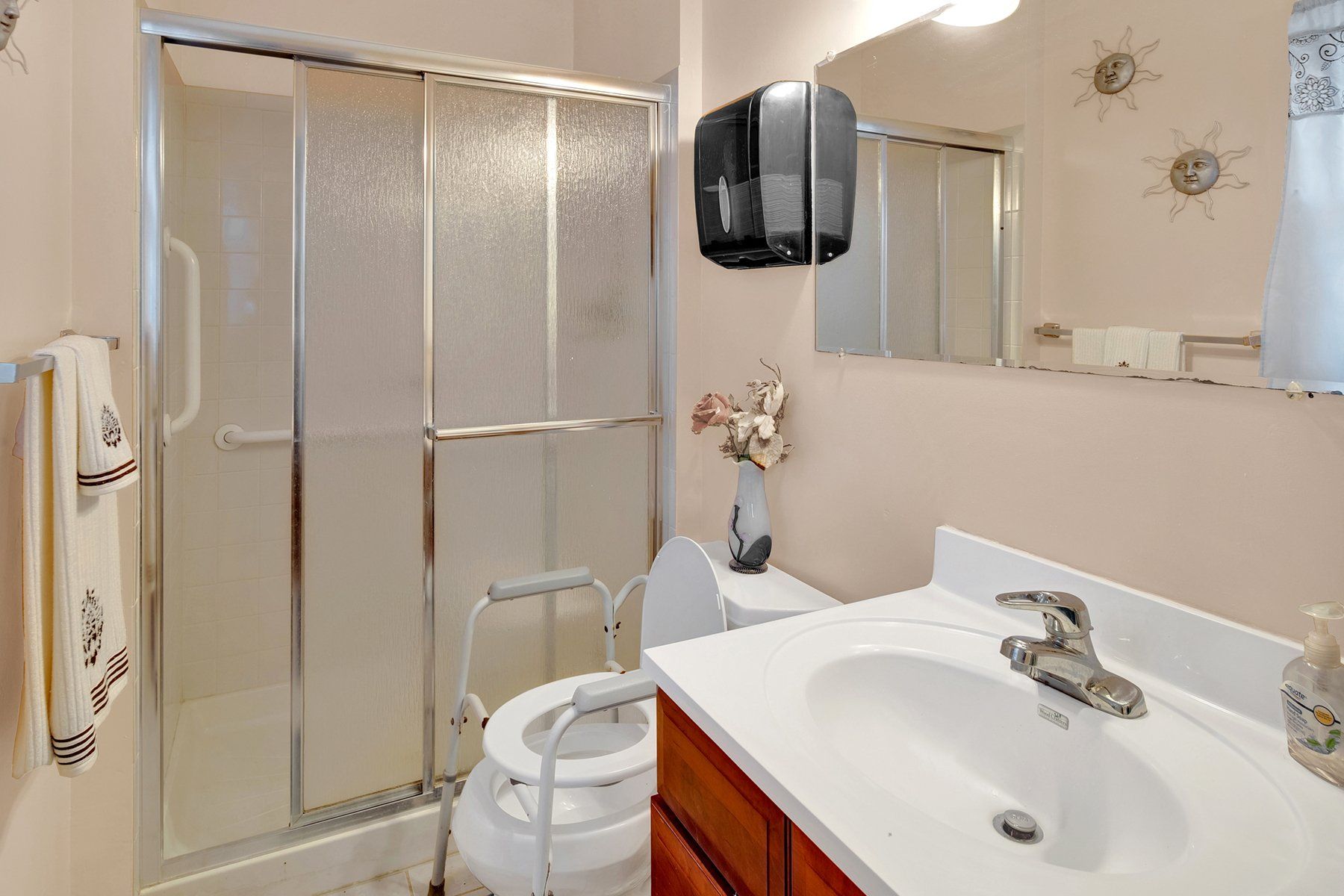 A bathroom with a toilet , sink , shower and mirror.