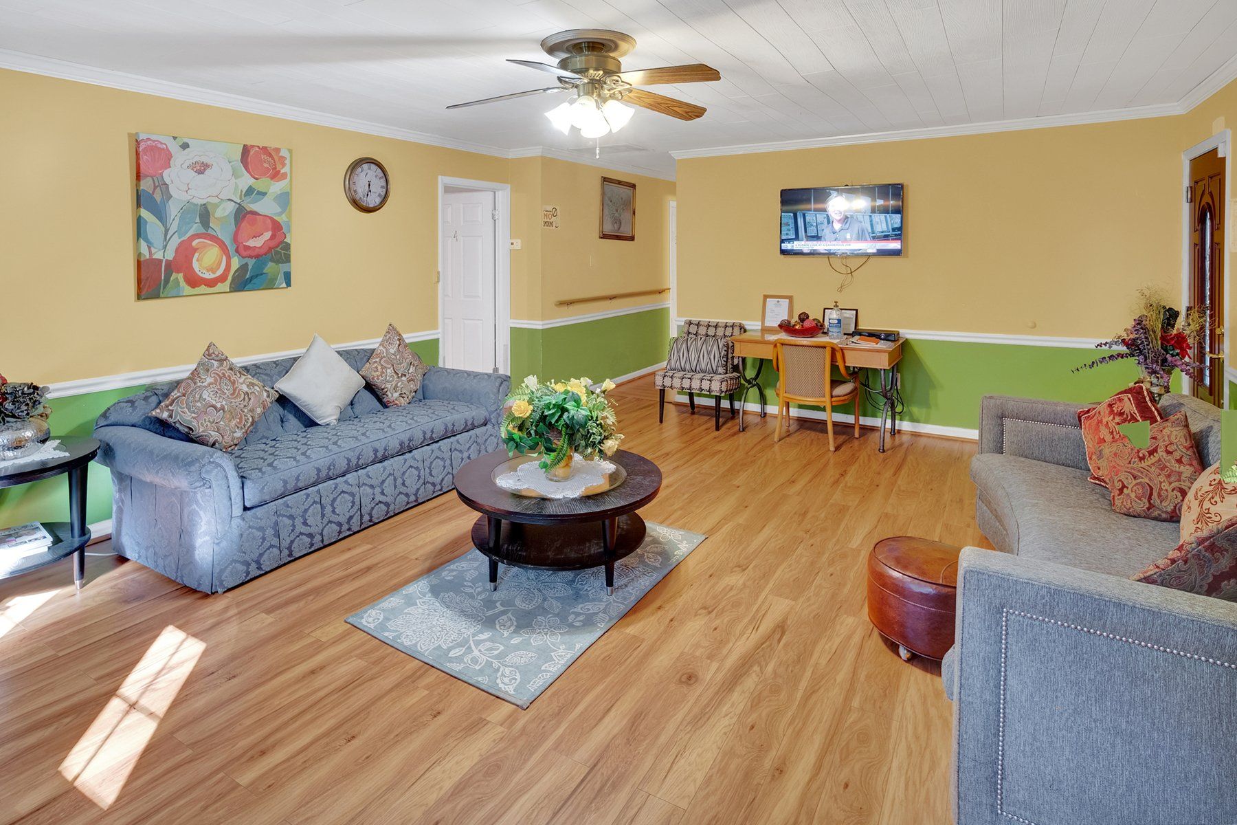 A living room with a couch , table , chairs and a ceiling fan.