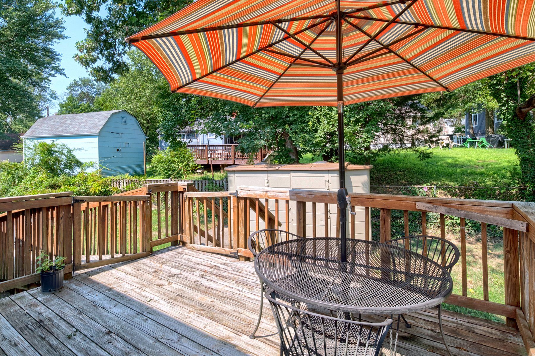 A wooden deck with a table and chairs and an umbrella.