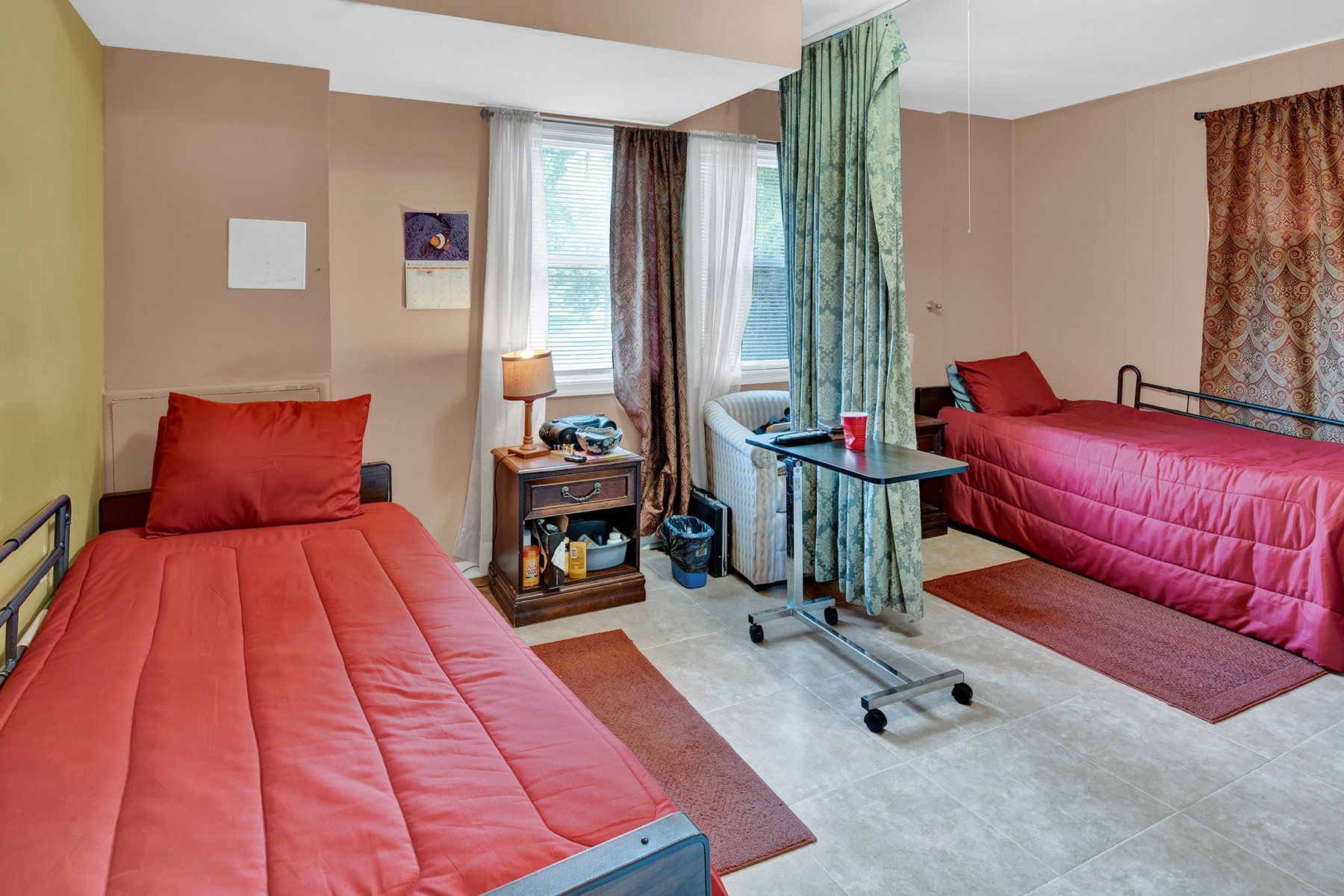 A bedroom with two beds , a nightstand , and a table.
