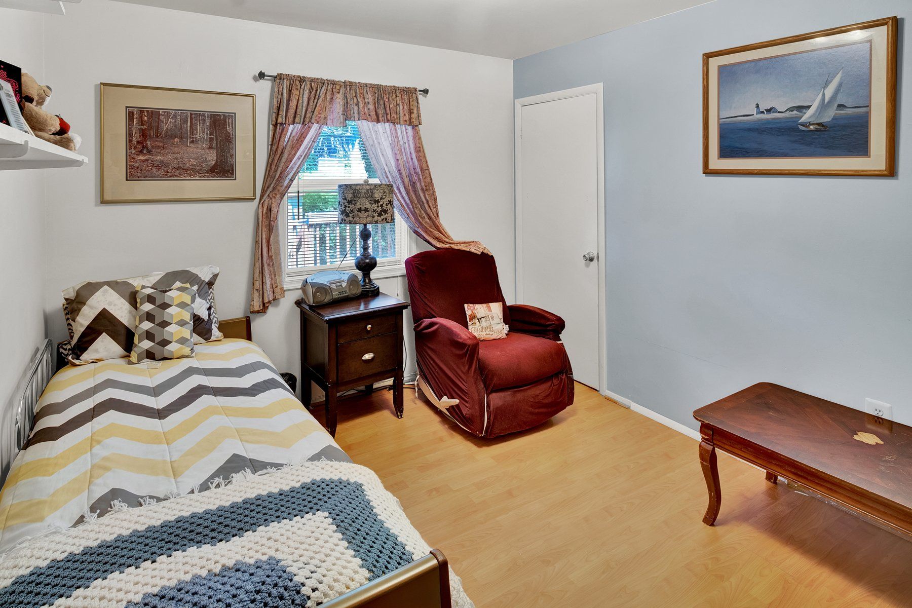 A bedroom with a bed , chair , nightstand and coffee table.