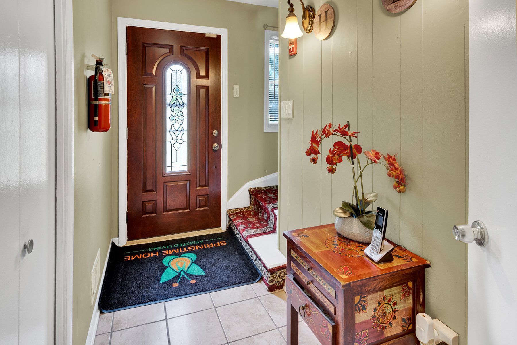A hallway with a wooden table and a fire extinguisher on the wall.