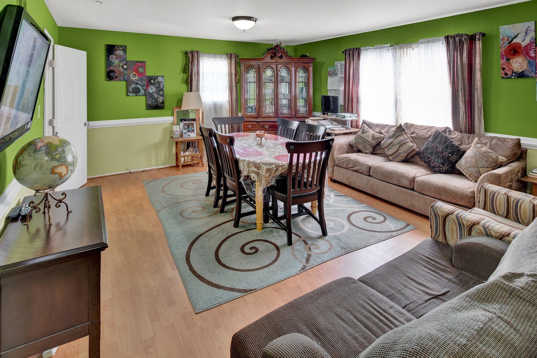 A living room with a couch , chairs , a table and a television.