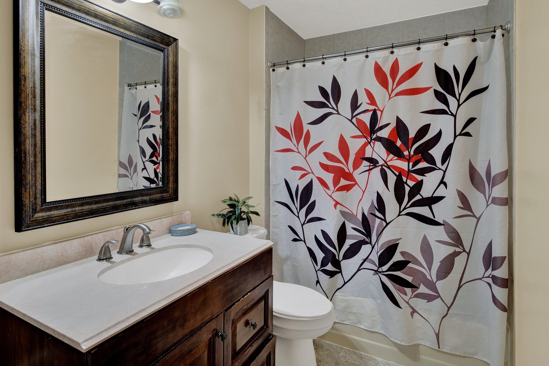 A bathroom with a sink , toilet , shower curtain and mirror.