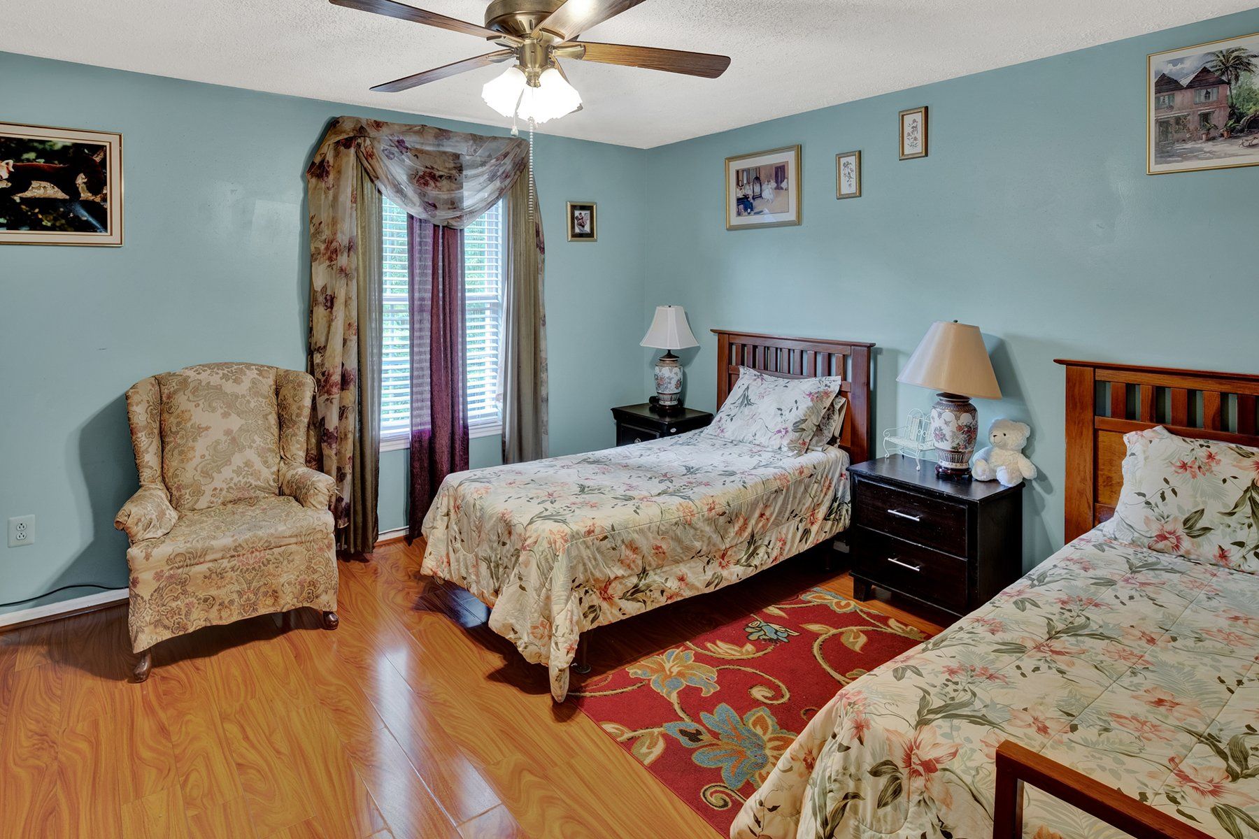 A bedroom with two beds , a chair and a ceiling fan.