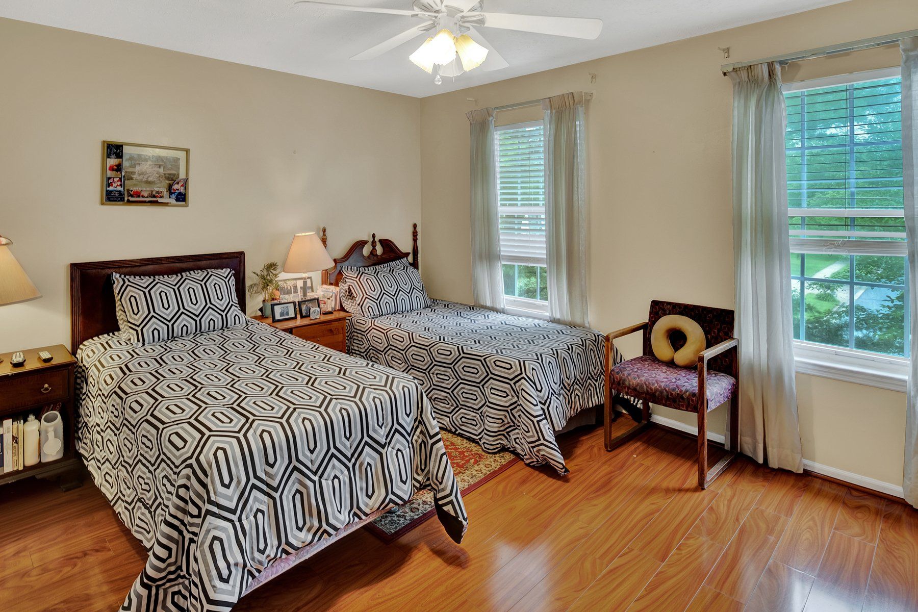 A bedroom with two beds , a chair and a ceiling fan.